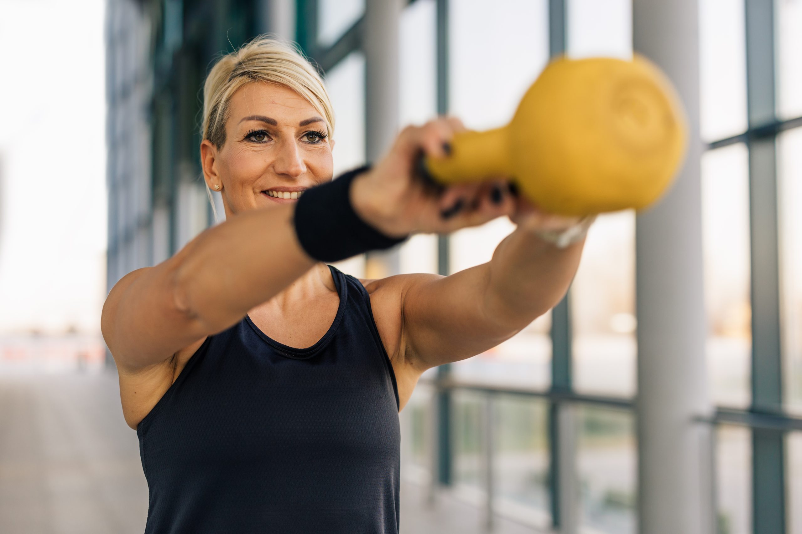 Caucasian middle aged woman is lifting a weight in the gym