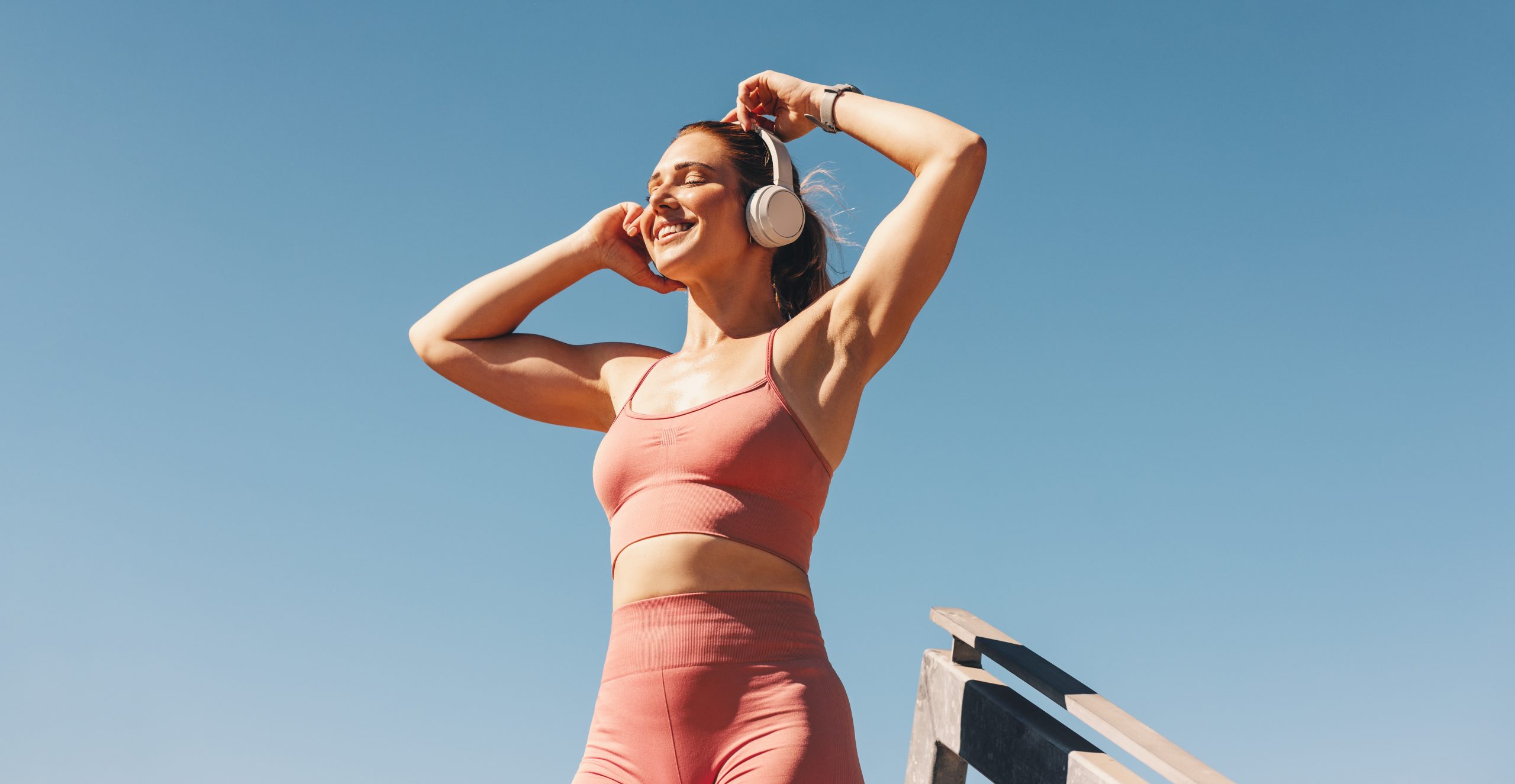 Woman listening to music on headphones outdoors.