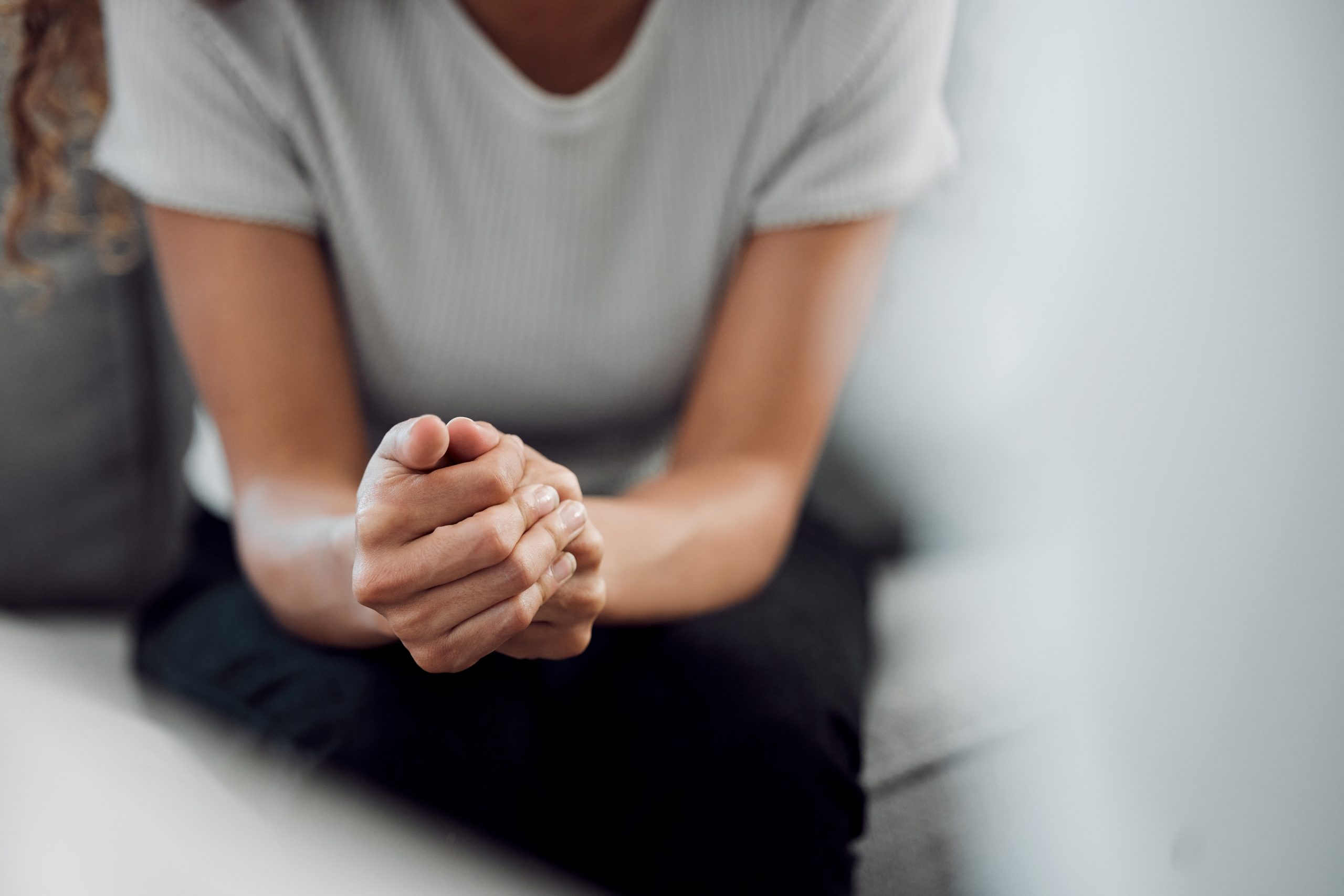 Close-up of a person sitting with clasped hands, conveying stress, anxiety, and health concerns.