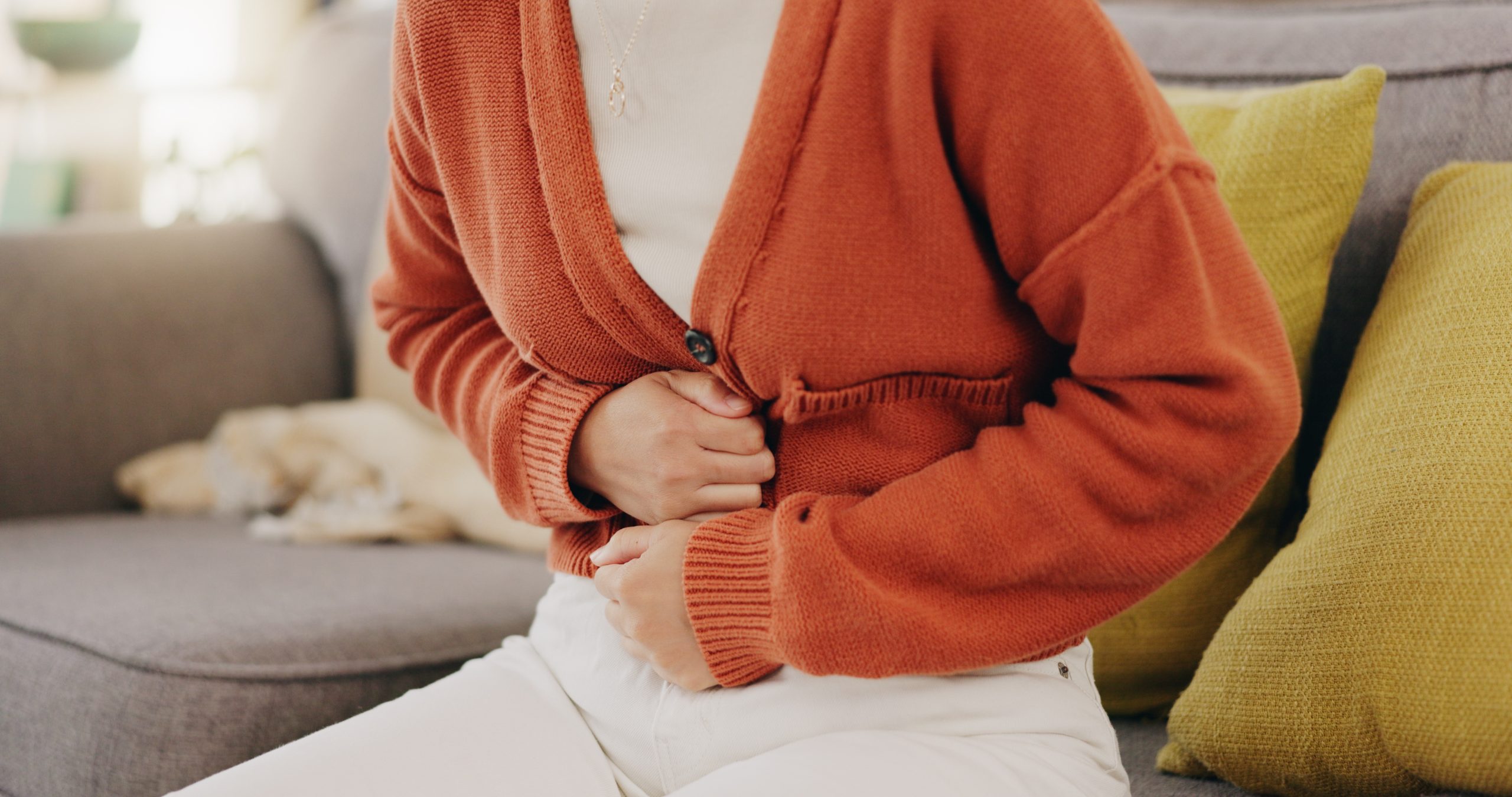 Woman holding her lower abdomen in discomfort from cramps.