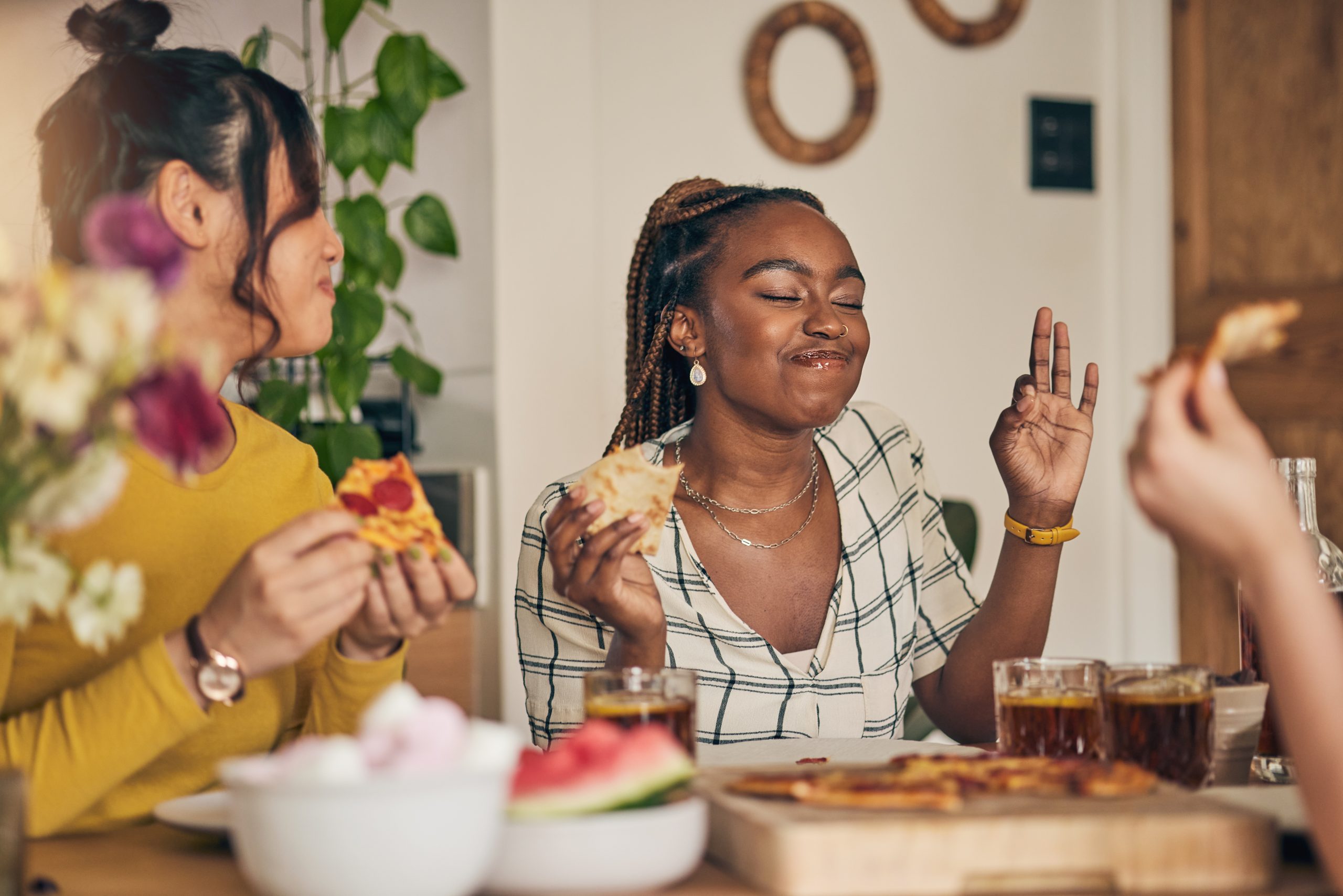 Group of friends sharing pizza and drinks together around a dining table.